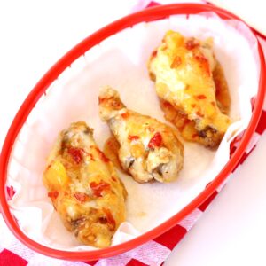 Three chicken wings in basket with Thai sweet chili sauce.