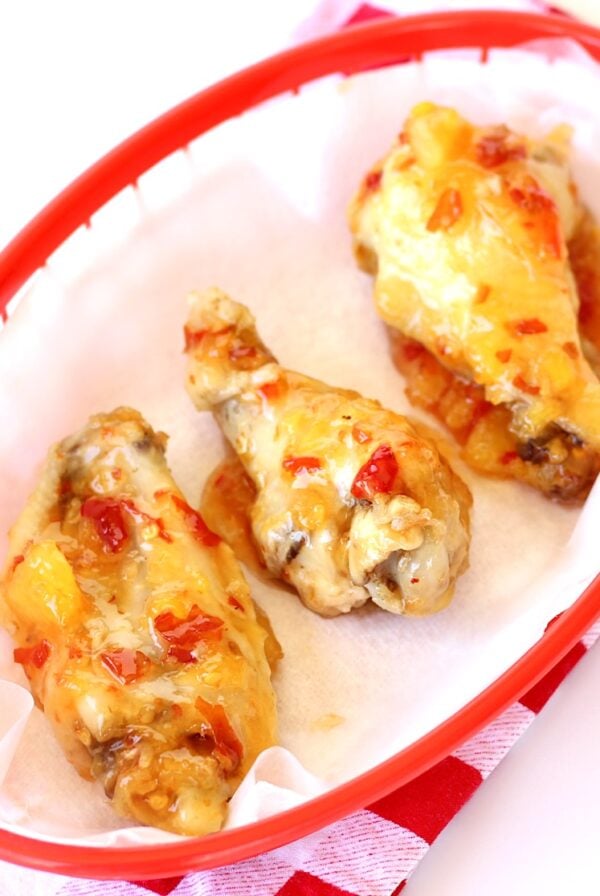 Three chicken wings in basket with Thai sweet chili sauce.