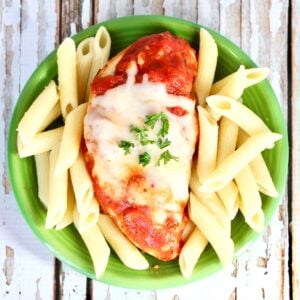 Chicken marinara on plate with mozzarella cheese on top and pasta to the side.
