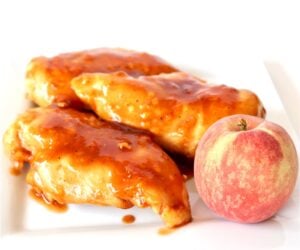 Three pieces of Chipotle chicken on plate with a peach.