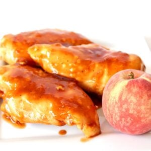 Three pieces of Chipotle chicken on plate with a peach.