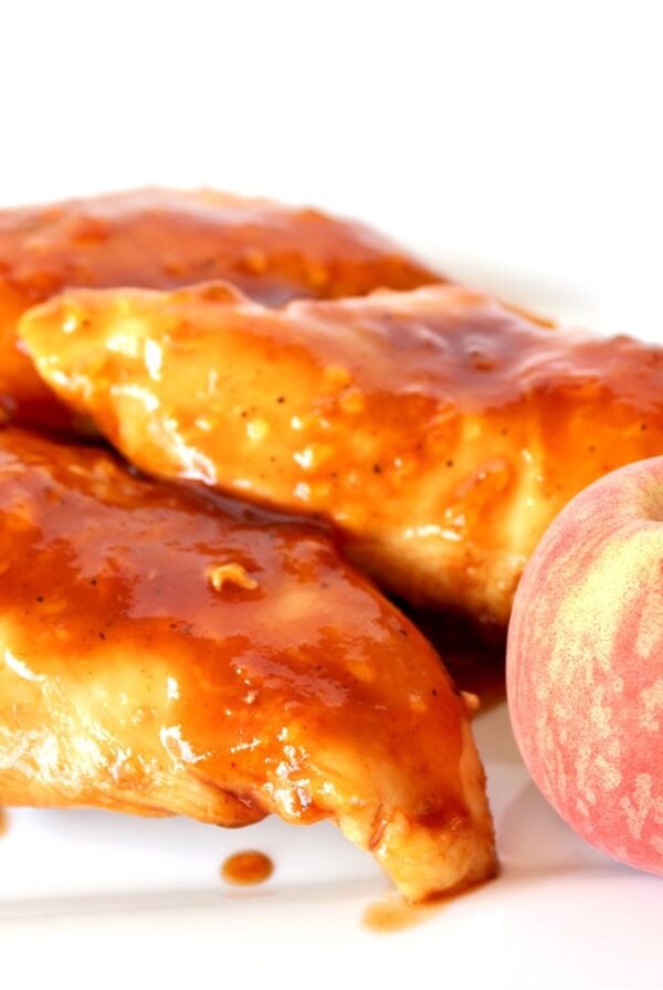 Three pieces of Chipotle chicken on plate with a peach.