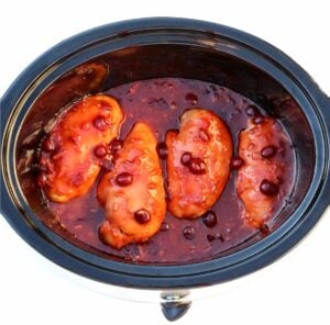 Four pieces of cranberry orange chicken in crockpot.
