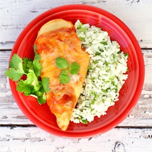 Enchilada Chicken with side of rice on plate.