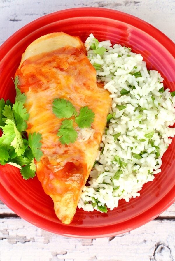 Enchilada Chicken with side of rice on plate.
