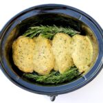 Four pieces of Garlic Herb Chicken in crock pot with rosemary.