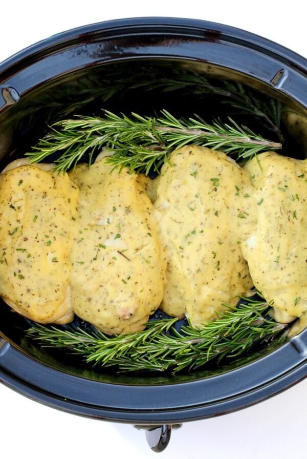 Four pieces of Garlic Herb Chicken in crock pot with rosemary.