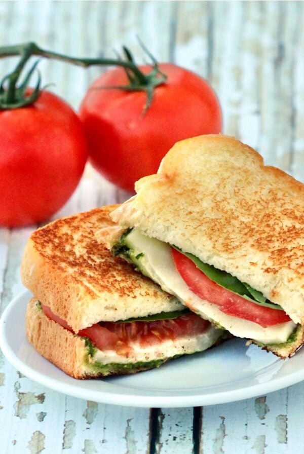 Italian Mozzarella Grilled Cheese sandwich on plate with tomatoes in the background.