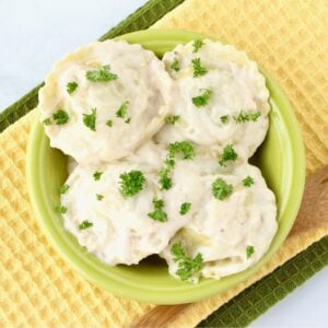 Ravioli Alfredo in small bowl with parsley on top.