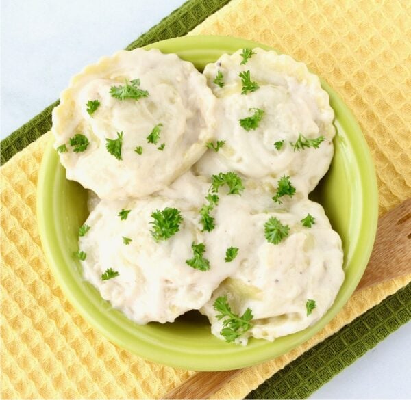 Ravioli Alfredo in small bowl with parsley on top.