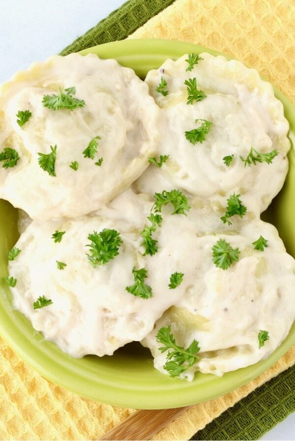 Ravioli Alfredo in small bowl with parsley on top.