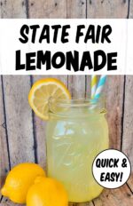 Homemade state fair lemonade in mason jar with straws, and lemons to the side.