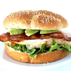 Grilled California chicken sandwich with ranch, bacon, and avocado slices on bun.