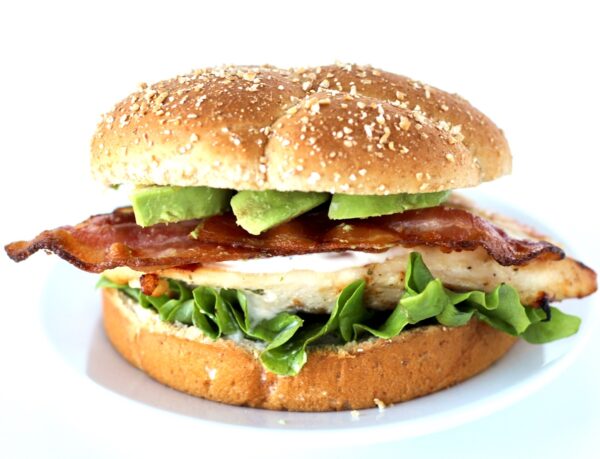 Grilled California chicken sandwich with ranch, bacon, and avocado slices on bun.