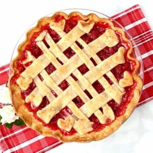 Fresh homemade raspberry pie with lattice crust in pie dish.