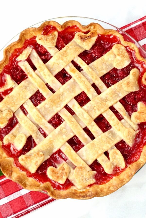 Fresh homemade raspberry pie with lattice crust in pie dish.