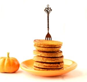 Stack of pumpkin spice pancakes on plate with fork inserted.