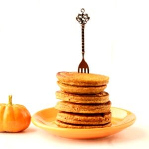 Stack of pumpkin spice pancakes on plate with fork inserted.