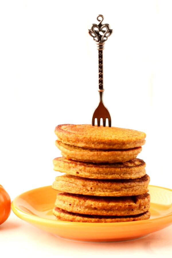 Stack of pumpkin spice pancakes on plate with fork inserted.