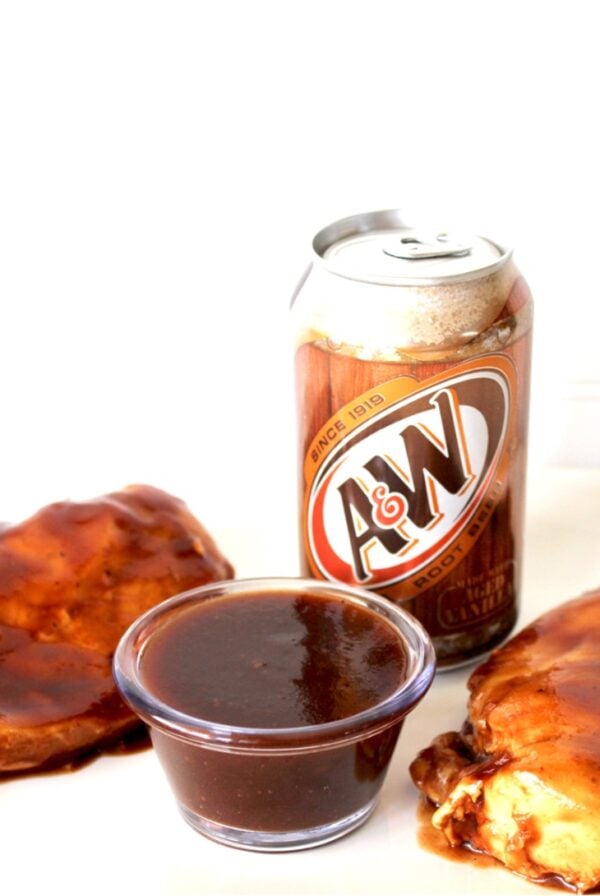 Two pieces of root beer chicken on plate with barbecue sauce and can of A&W root beer.