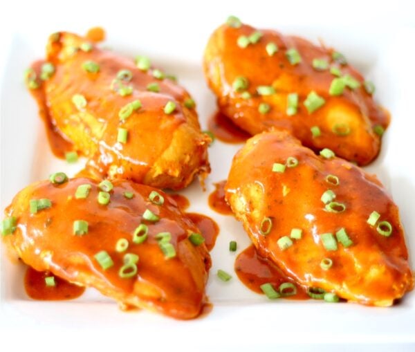 Four pieces of ranch buffalo chicken on plate, garnished with green onions.