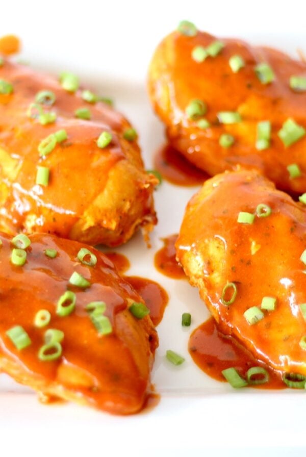 Four pieces of ranch buffalo chicken on plate, garnished with green onions.