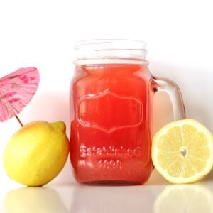 Pineapple lemonade punch in mason jar mug with lemons to the side.