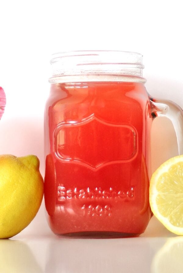 Pineapple lemonade punch in mason jar mug with lemons to the side.