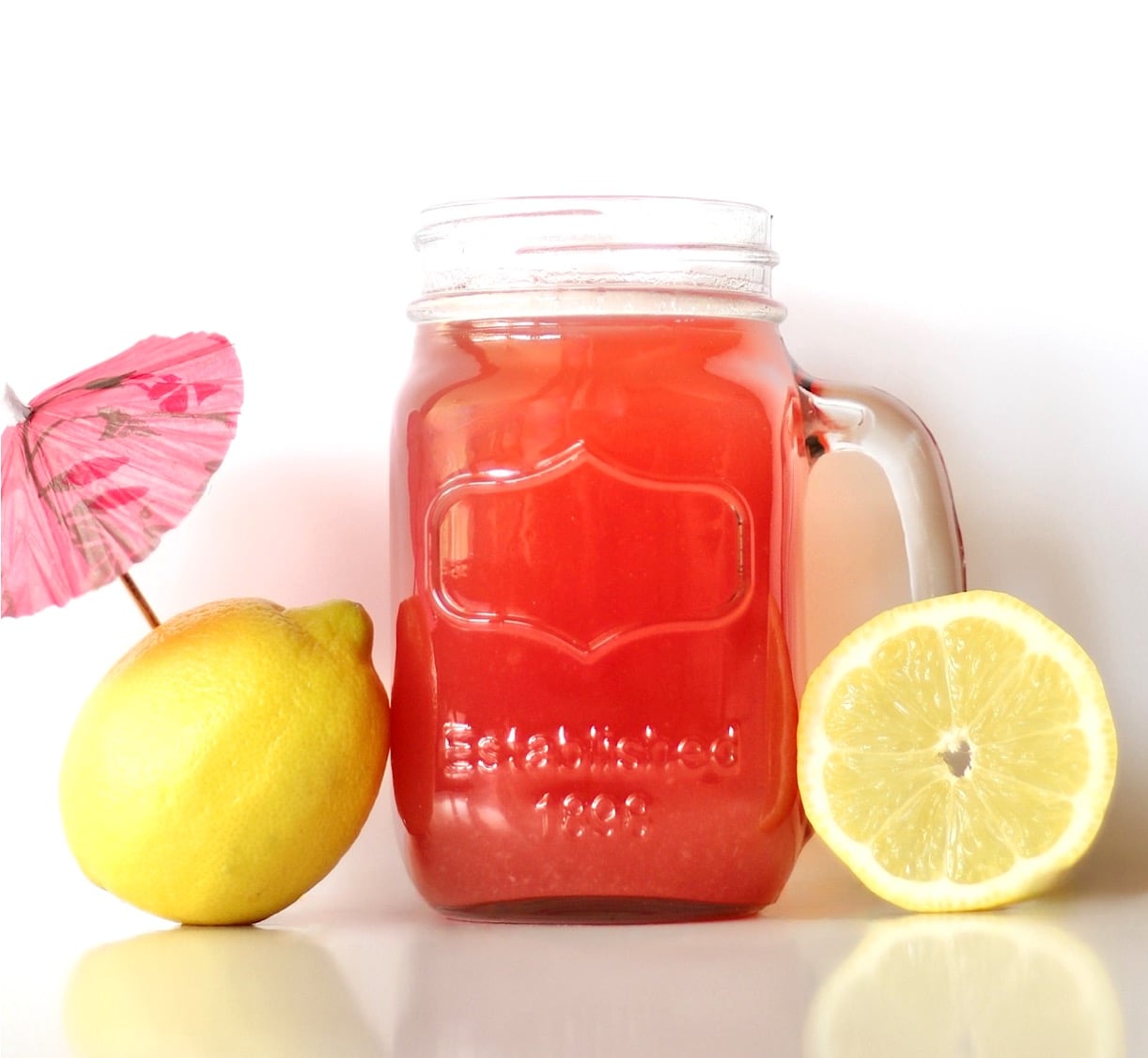 Pineapple lemonade punch in mason jar mug with lemons to the side.