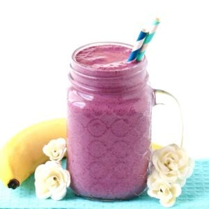 Berry Banana Smoothie in mason jar mug with straws, and banana in background.