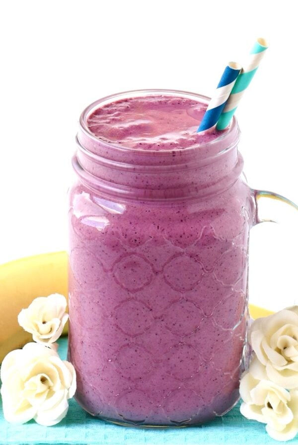 Berry Banana Smoothie in mason jar mug with straws, and banana in background.