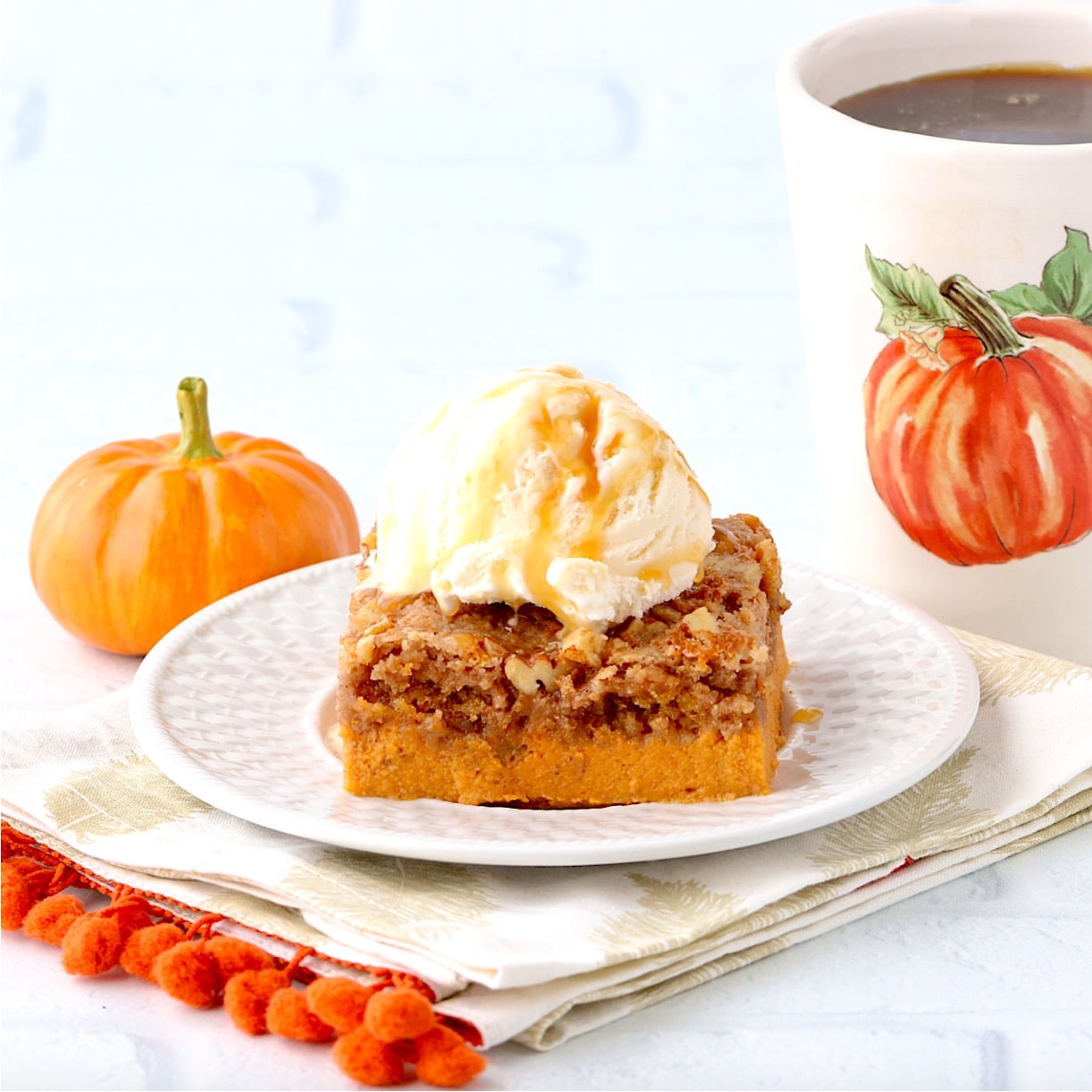 Piece of pumpkin dump cake on plate with scoop of ice cream on top.