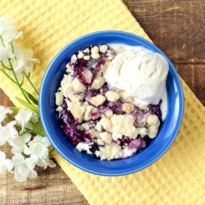 Blueberry cobbler with cake mix in small bowl with scoop of vanilla ice cream.