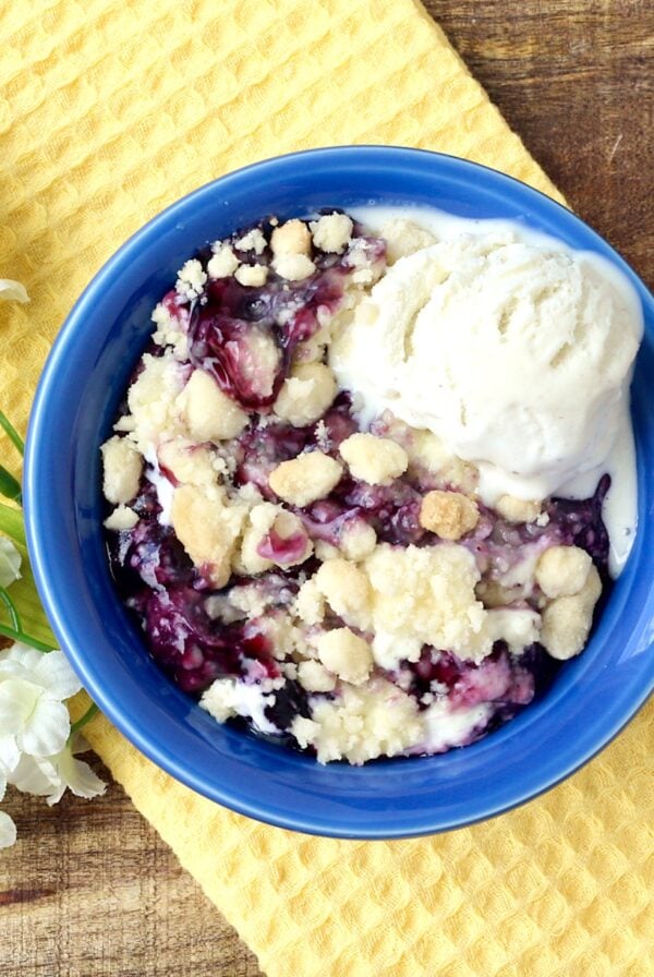 Blueberry cobbler with cake mix in small bowl with scoop of vanilla ice cream.