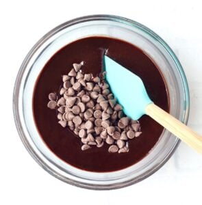 Brownie batter in mixing bowl with chocolate chips and spatula.