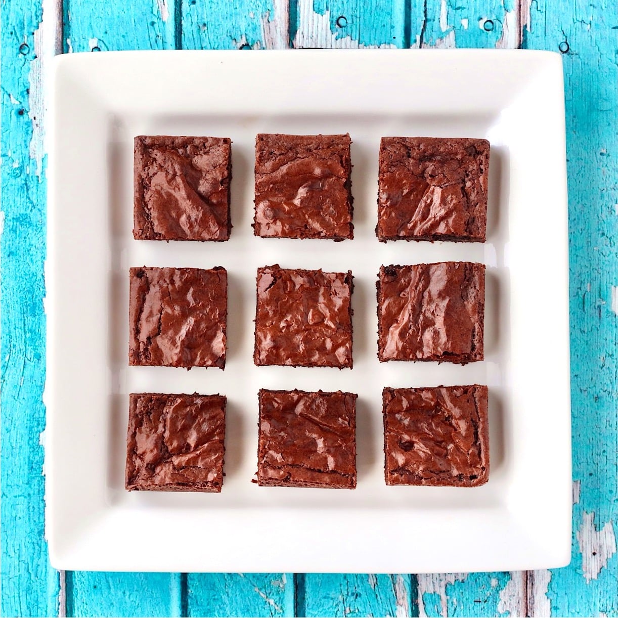 Nine chocolate chip brownies on plate.