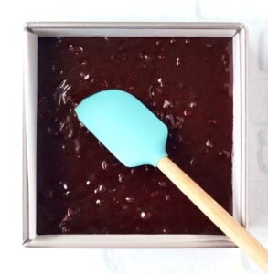 Chocolate chip chocolate brownie batter in pan with spatula.