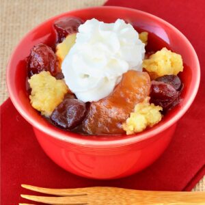 Apple Cranberry Dump Cake in small bowl with whip cream on top.