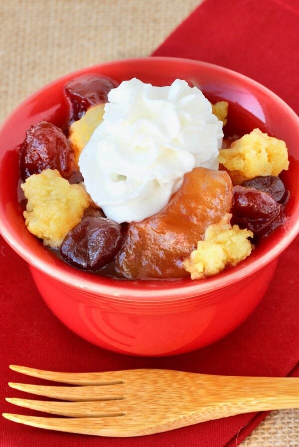 Apple Cranberry Dump Cake in small bowl with whip cream on top.