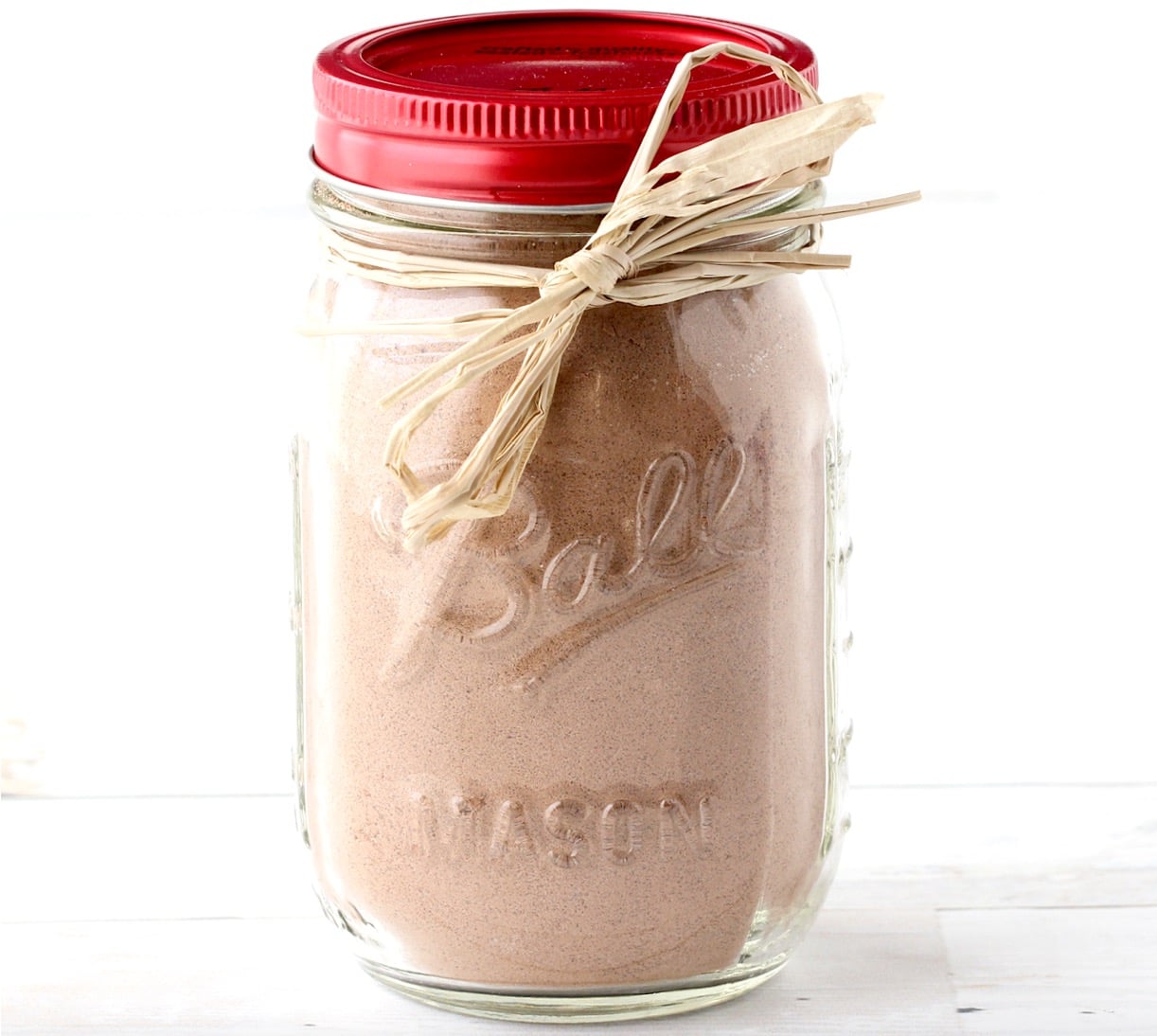 Homemade brownie mix in mason jar with red lid and bow tied around jar.