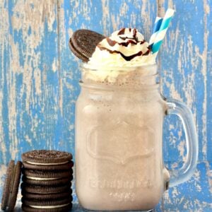 Oreo Milkshake in mason jar mug with whip cream, chocolate syrup, and Oreo cookie on top.