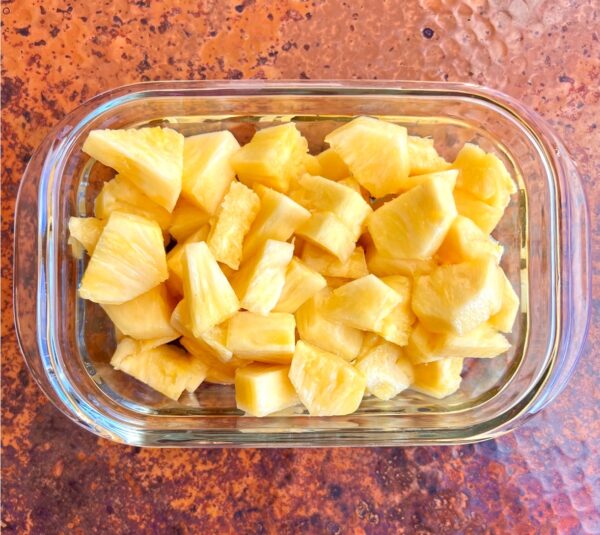 Cut fresh pineapple chunks in glass meal prep container.