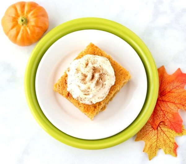 Slice of pumpkin angel food cake on plate with whip cream on top.