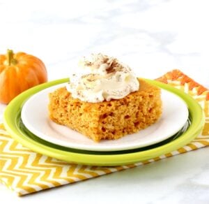 Pumpkin Angel Food Cake on plate with whip cream on top, and pumpkin in background.
