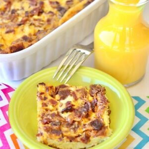 Bacon egg casserole in small dish with fork, and casserole dish in background.
