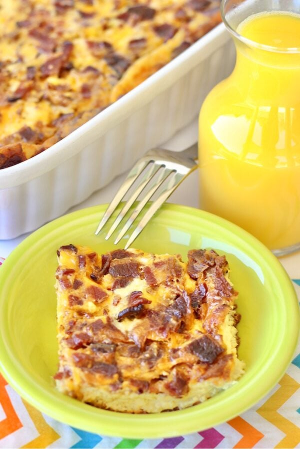 Bacon egg casserole in small dish with fork, and casserole dish in background.