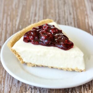 Slice of blackberry cream cheese pie with graham cracker crust on plate.