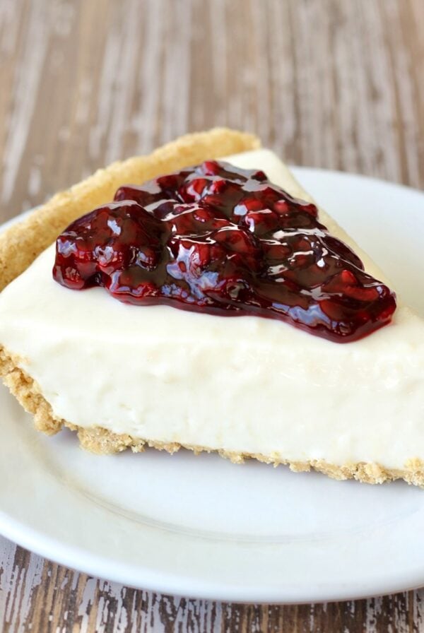 Slice of blackberry cream cheese pie with graham cracker crust on plate.