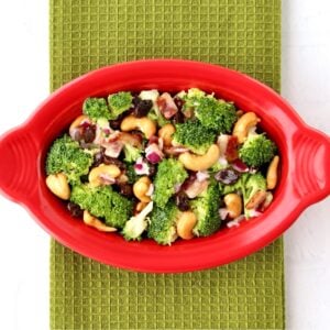 Broccoli raisin salad with cashews and bacon in red dish.