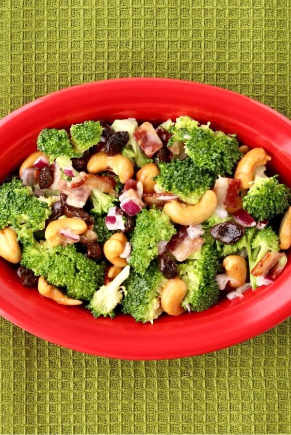 Broccoli raisin salad with cashews and bacon in red dish.
